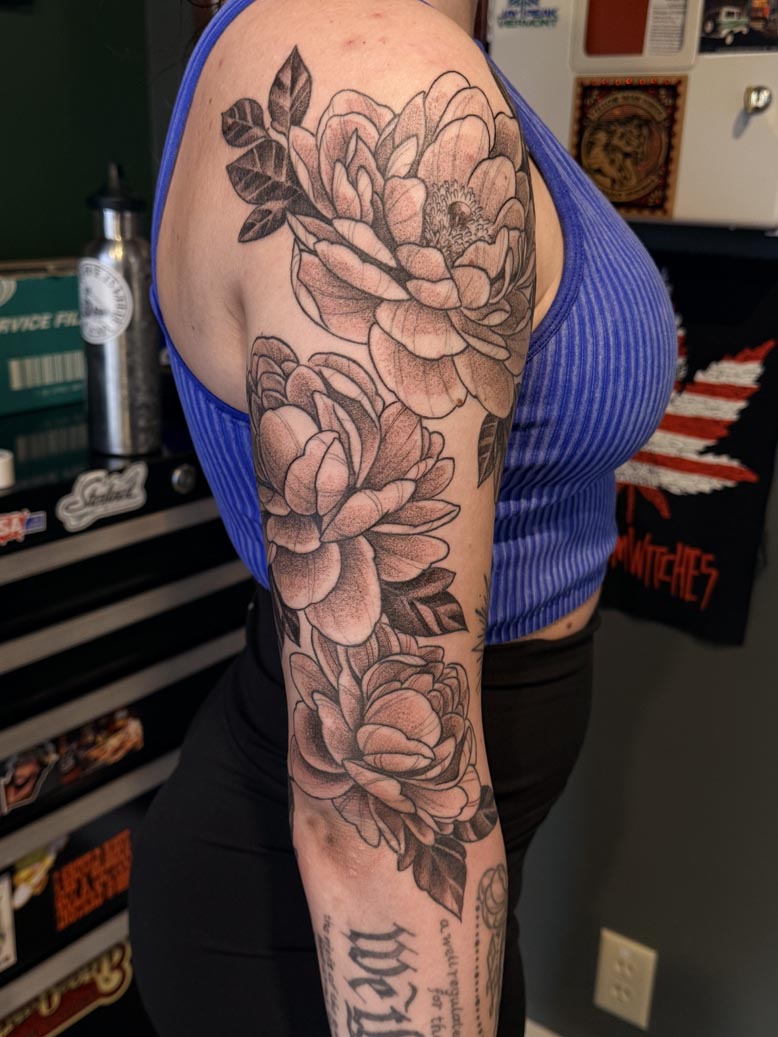 Floral black ink arm tattoo