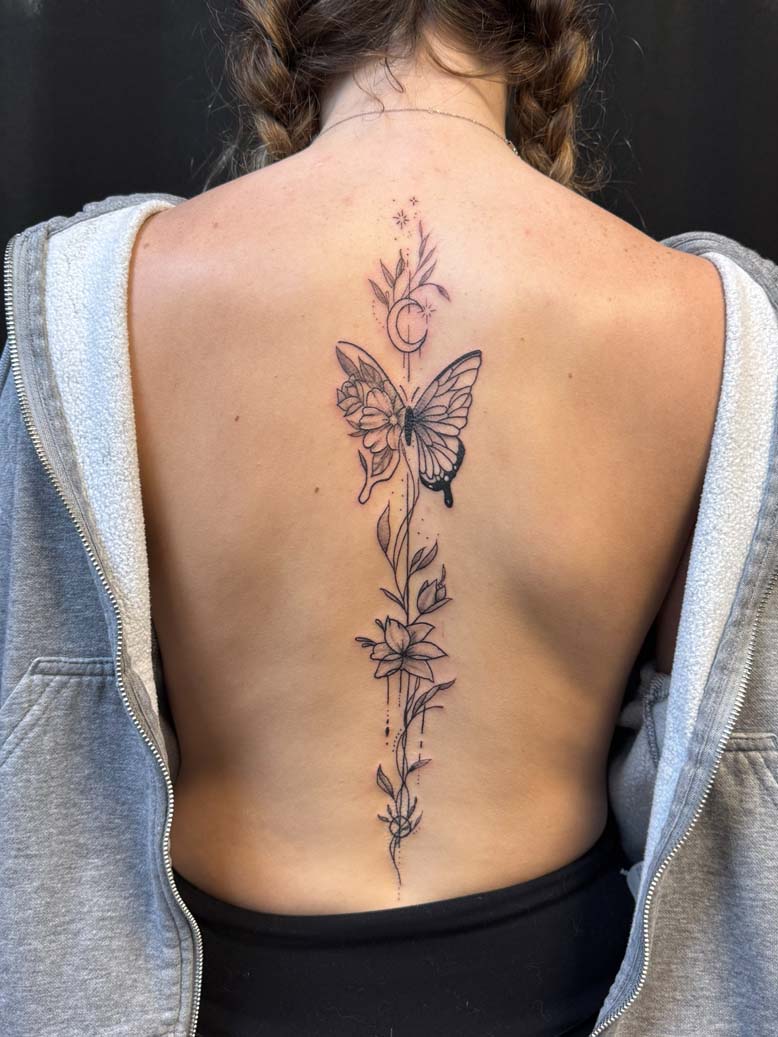 Black ink butterfly and plant spine tattoo
