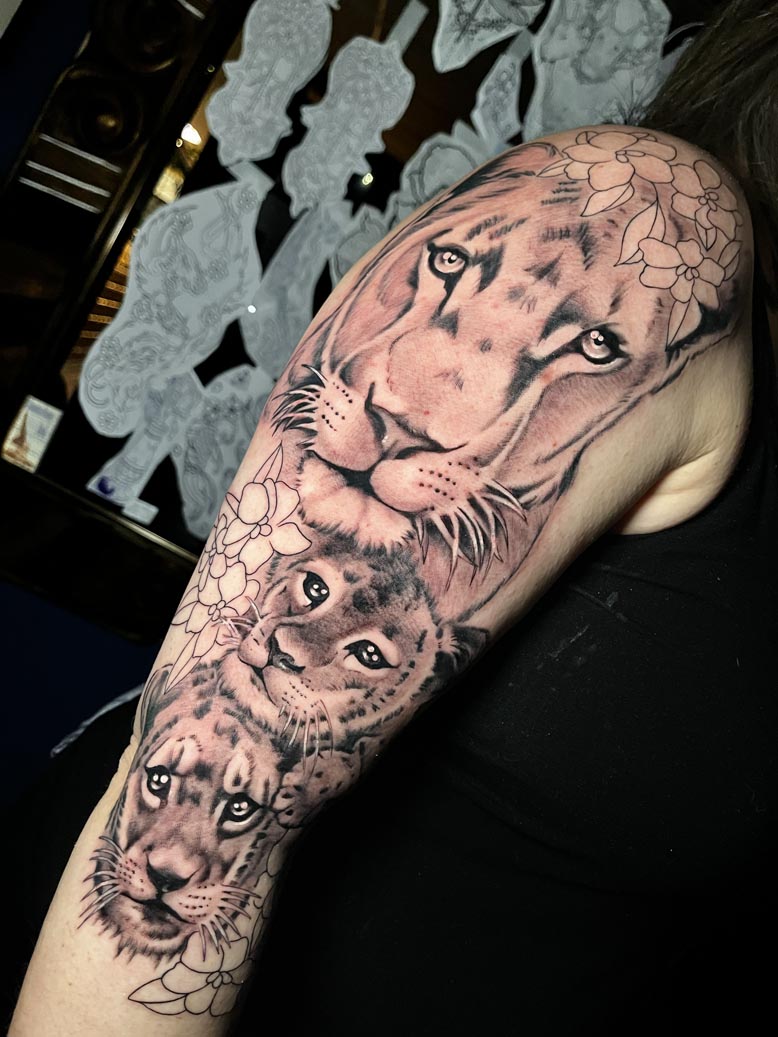 Lioness and cubs black ink arm tattoo
