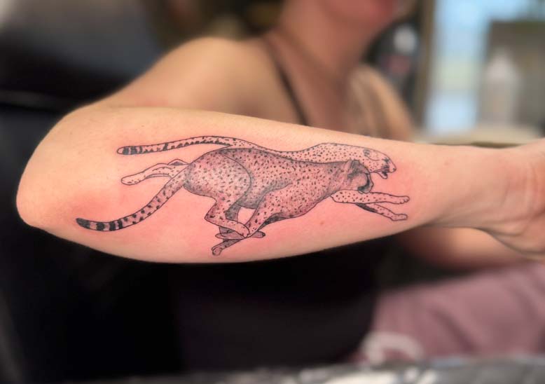 A forearm tattoo depicting two cheetahs running