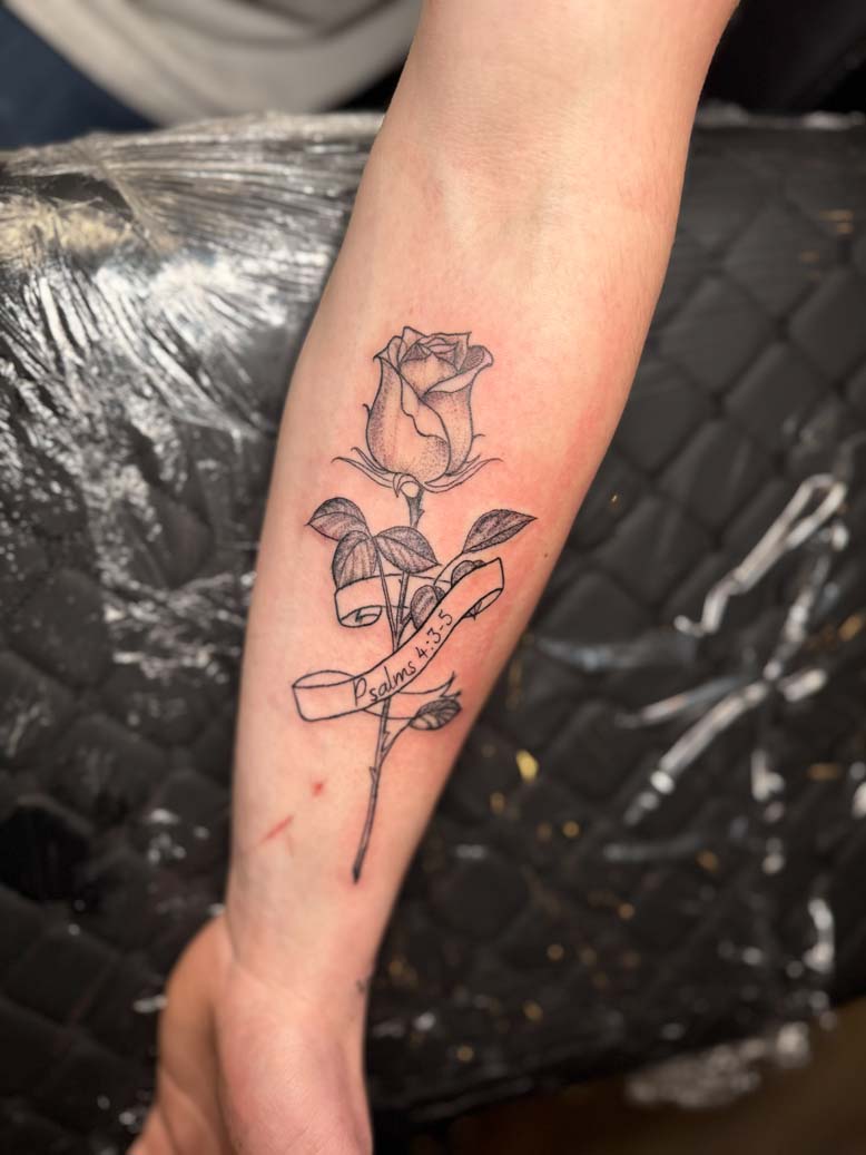A rose tattooed on a forearm with Psalms 4:3-5