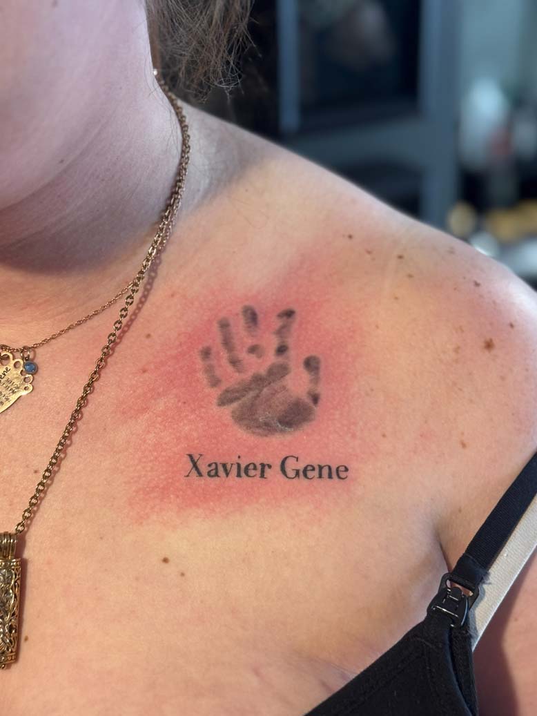 Baby Handprint tattooed on skin with the name "Xavier Gene" underneath it