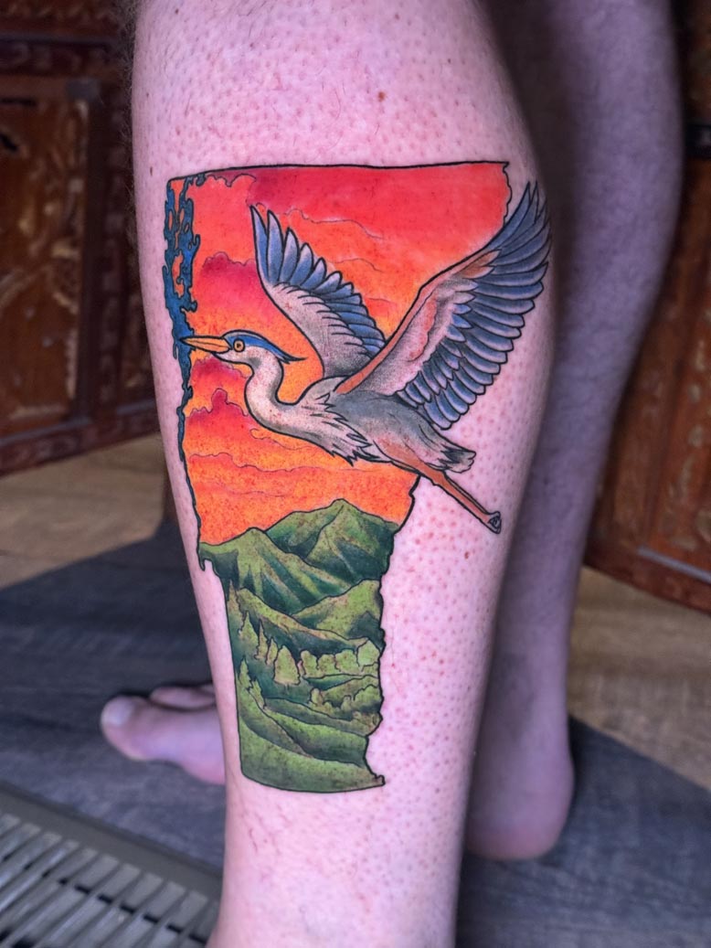 Colorful crane flying over the Vermont state shape tattoo