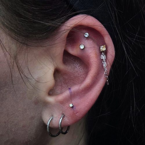 Close up of an ear with multiple piercings