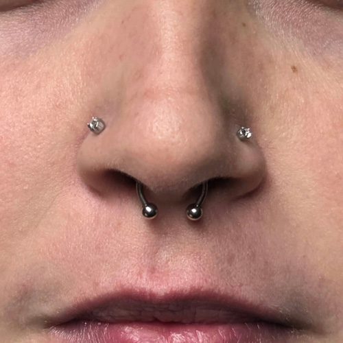 Close up of a nose with both nostrils pierced and a septum ring